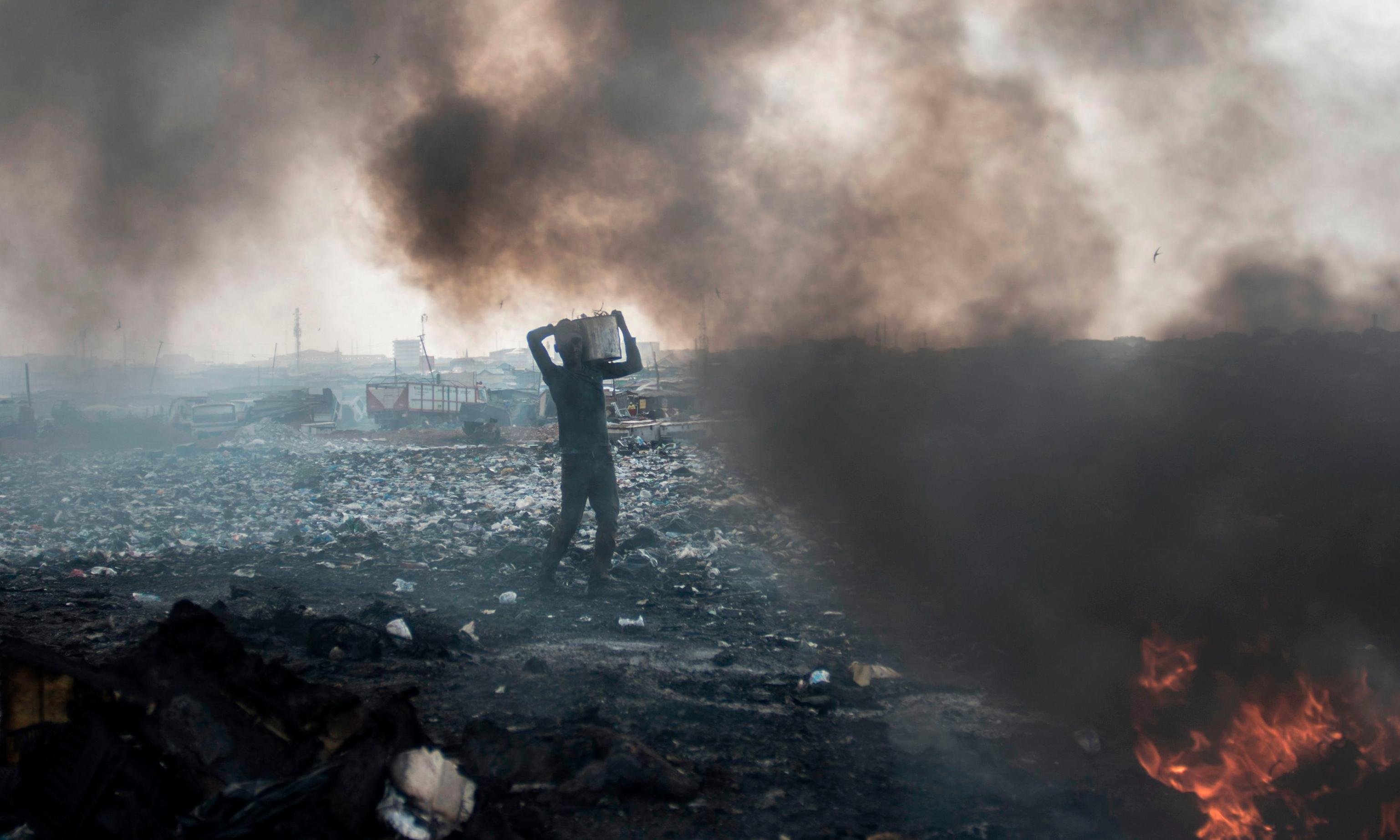 Man burning electronic waste in a landfill.