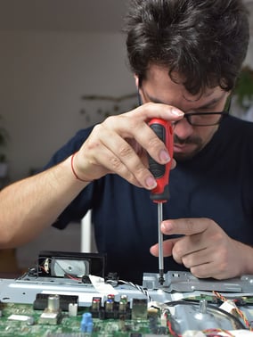 Man using a screw driver to repair an electronic device.
