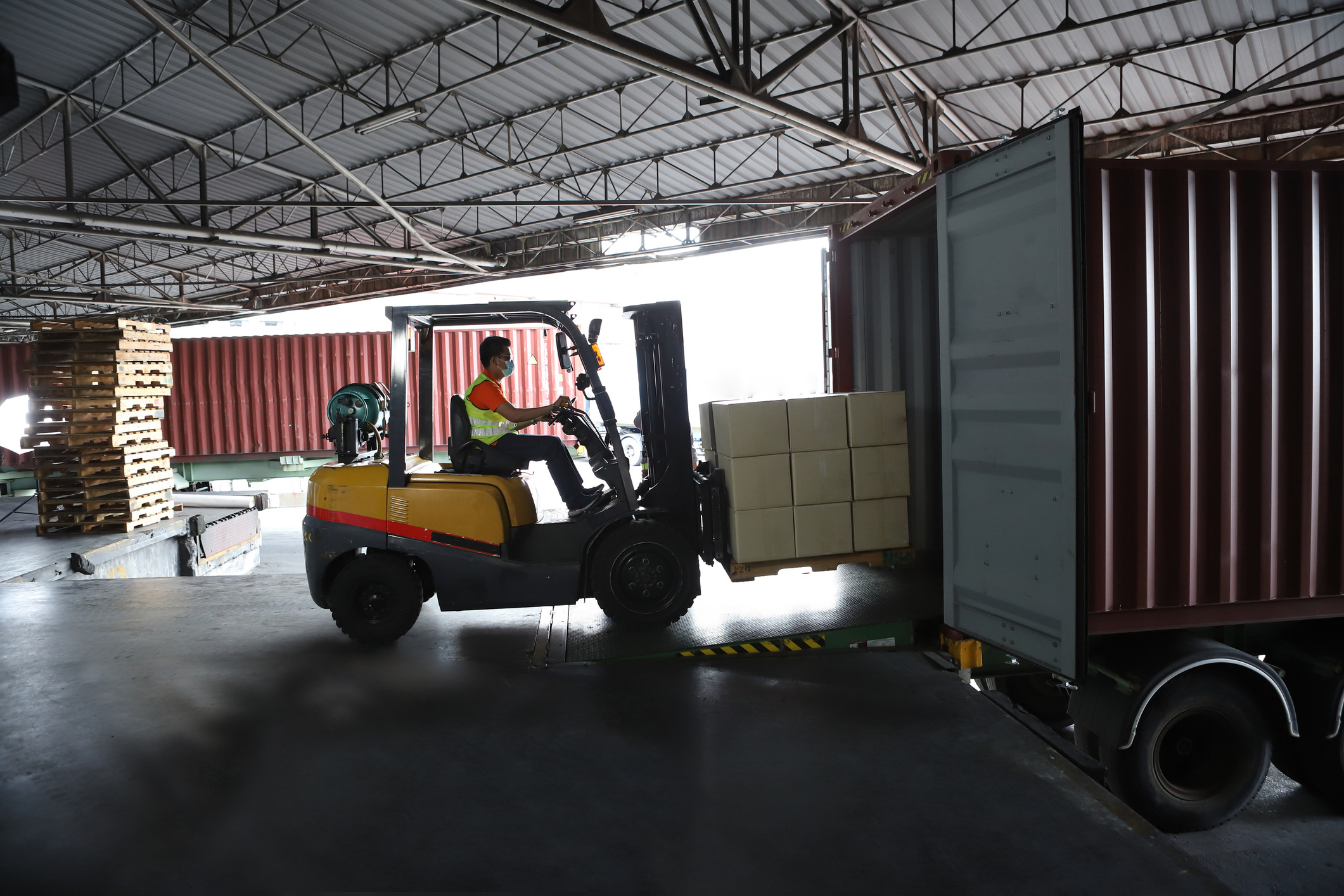 Person driving a forklift to load boxes into the back of a truck.