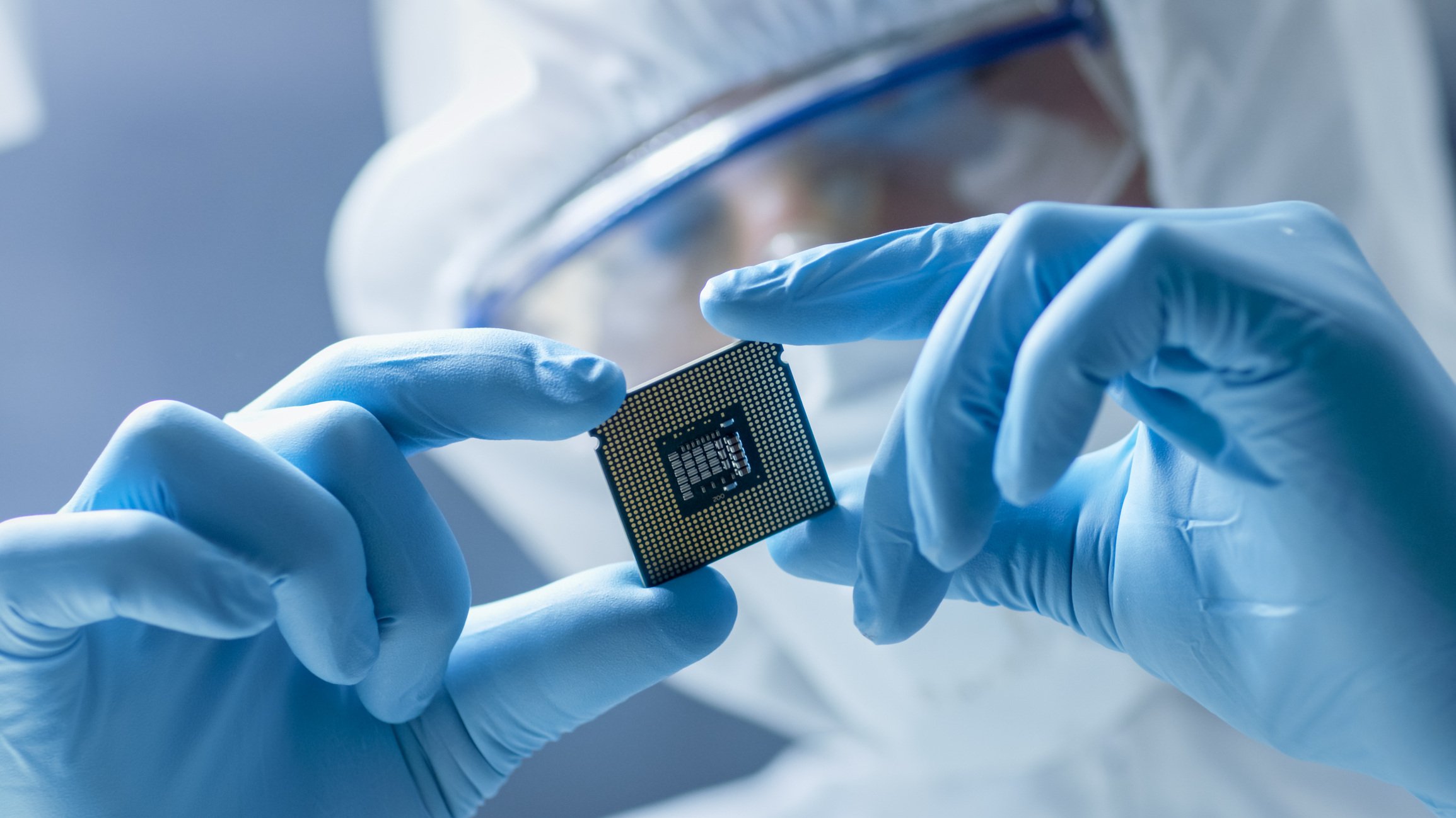 Person in a lab coat inspecting electronic component.